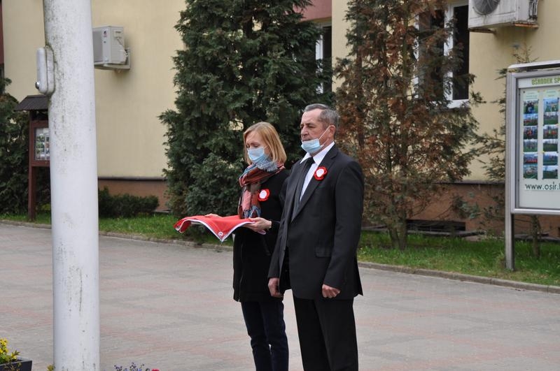 Przedstawiciele Urzędu Miasta Stoją przed masztem, na którym zawieszą flagę.