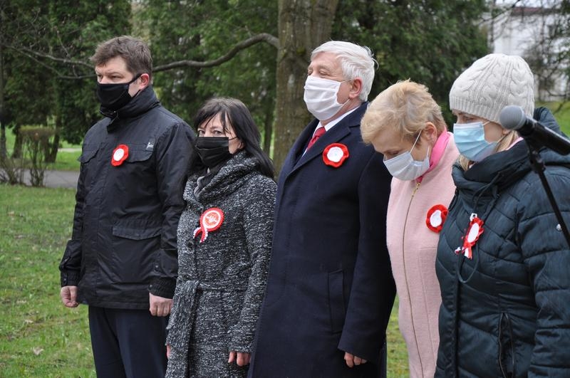 Delegacja samorządowców składająca kwiaty przy obelisku.