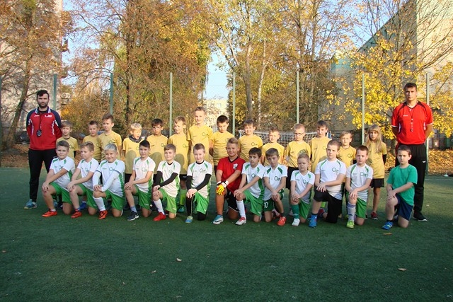 Grupa Orlików stojąca na zielonej murawie na tle drzew