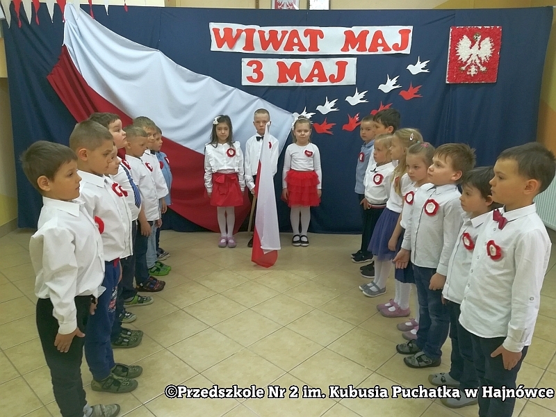 Dzieci z grupy I Tygryski ustawione w półkolu w tle patriotycznej dekoracji z nauczycielką i Dyrektor Przedszkola nr 2 im. Kubusia Puchatka Iwoną Raszkiewicz