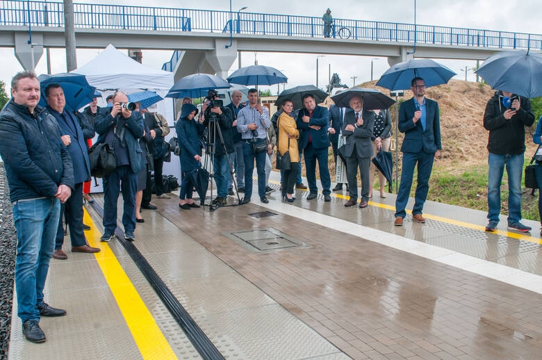 Grupa osób czekająca na peronie.