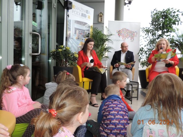 Na zdjęciu widać dzieci oraz osoby dorosłe siedzące na tarasie Książnicy Podlaskiej.