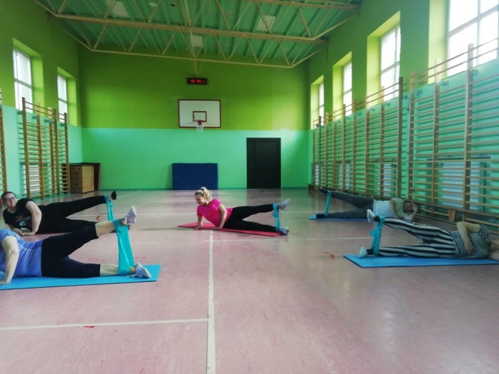grupa osób ćwicząca na matach z taśmami