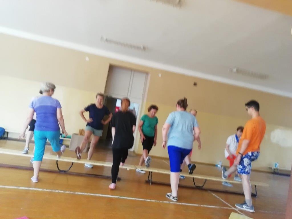 grupa osób ćwicząca na sali gimnastycznej przy ławce