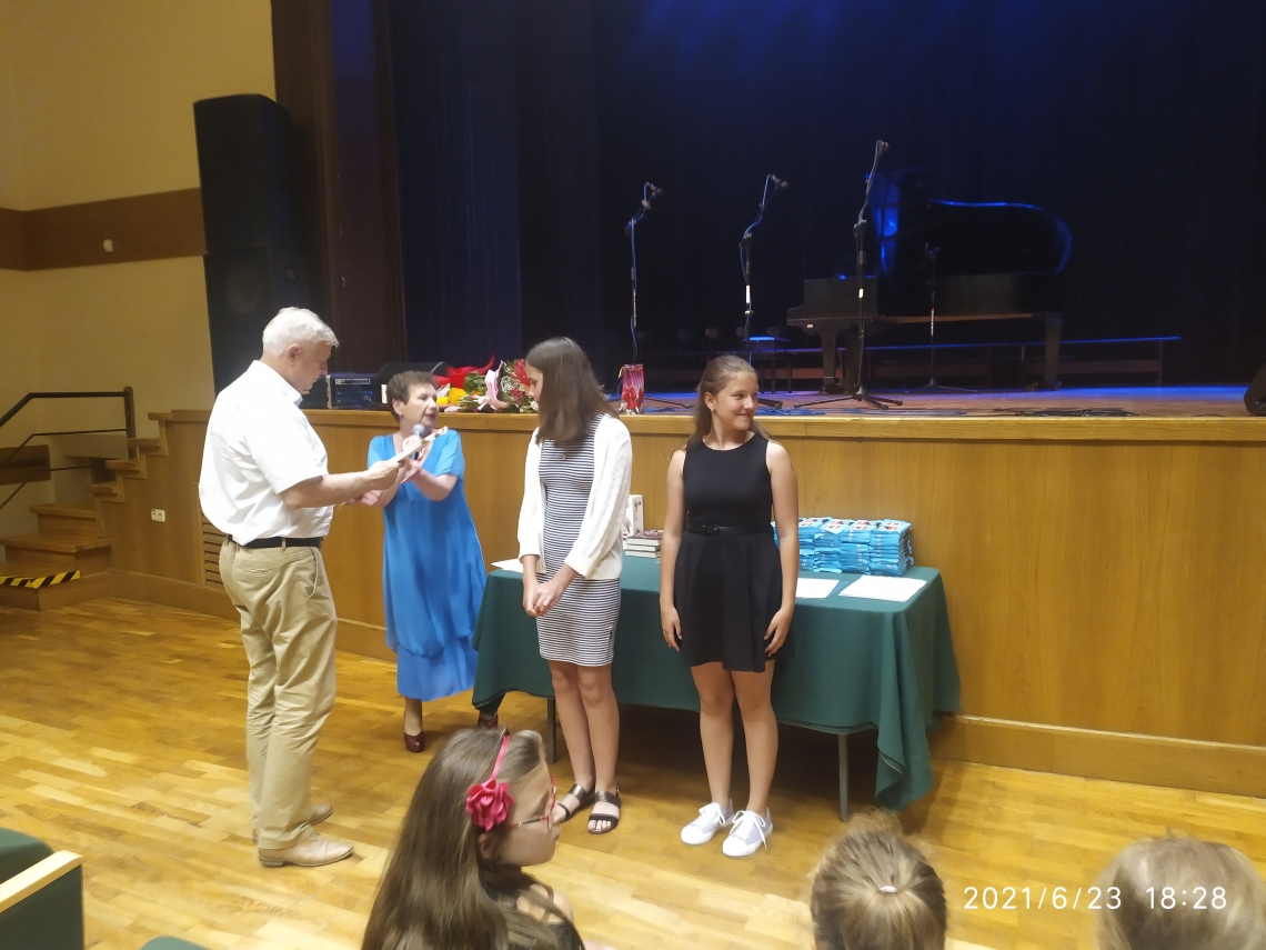 dzieci otrzymują dyplomy z okazji ukończenia roku szkolnego od Burmistrza Miasta