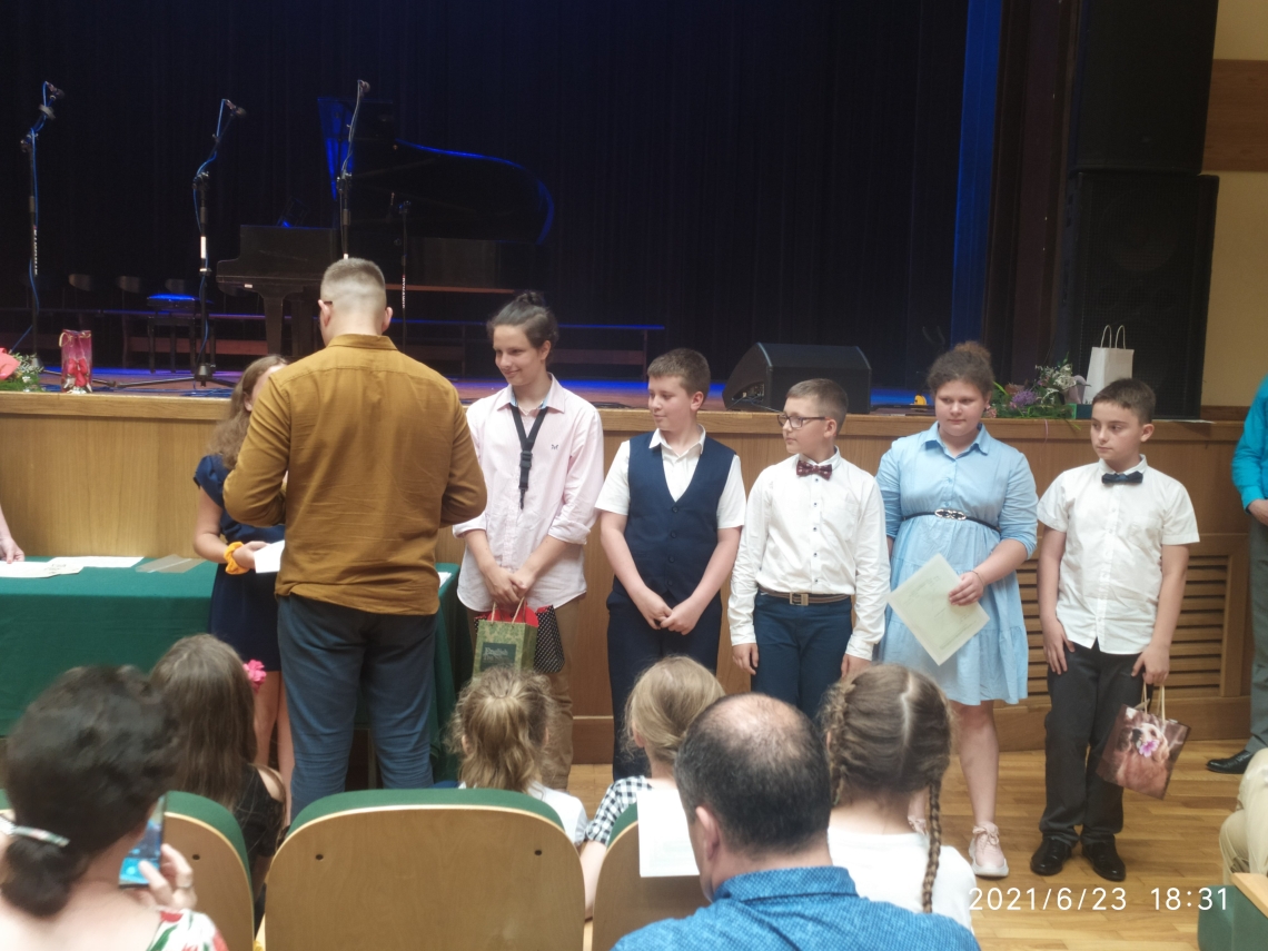 dzieci otrzymują dyplomy z okazji ukończenia roku szkolnego