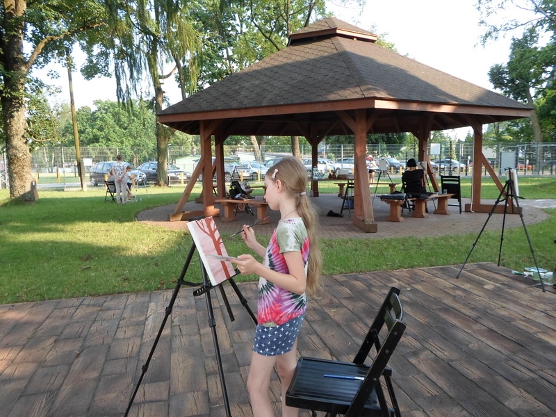 dziewczynka stoi przed sztalugą i maluje