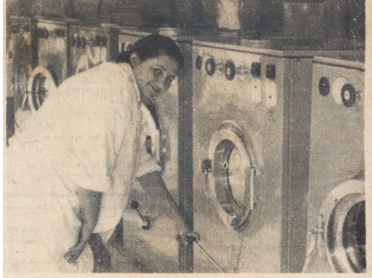 skan czarno-białego zdjęcia prasowego; na zdjęciu widoczny jest rząd pralek, przy których stoi obsługująca je kobieta