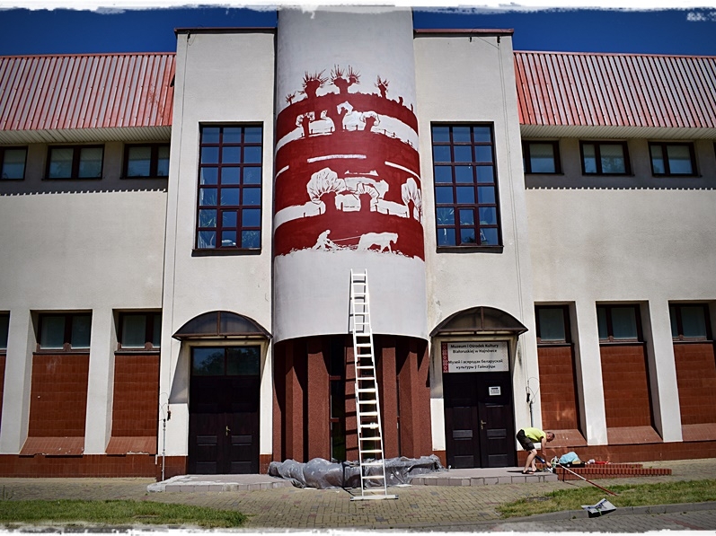 fragment budynku muzeum białoruskiego z widocznym na środku dużym muralem w kolorze czerwonym