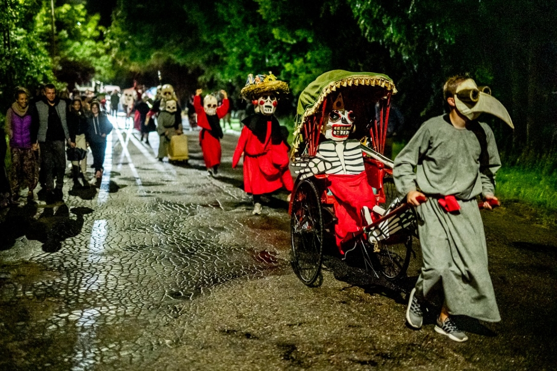 w nocnej scenerii alejkami parku spacerują przebrani aktorzy, obok nich widzowie