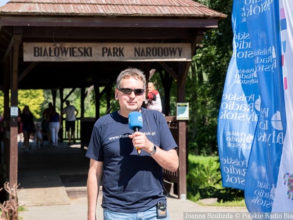 dziennikarz z Radia Białystok stoi przed bramą do Białowieskiego Parku Narodowego