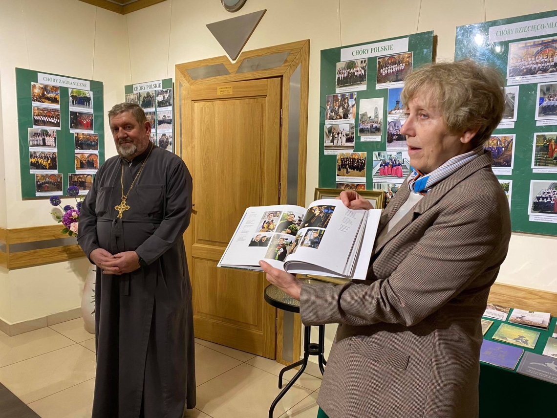 redaktora albumu jubileuszowego prezentuje publikację, obok niej z lewej strony stoi duchowny