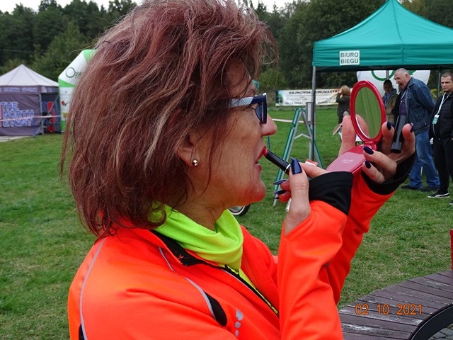 Kobieta w czerwonej kurtce trzyma w ustach gwizdek