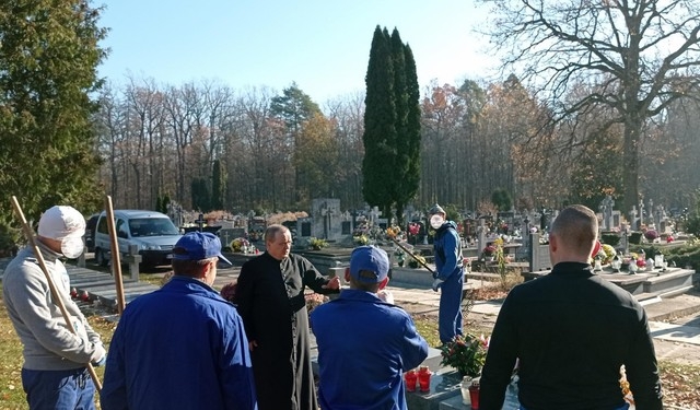 proboszcz opowiada historię pomordowanych stojąc przy pomnikach