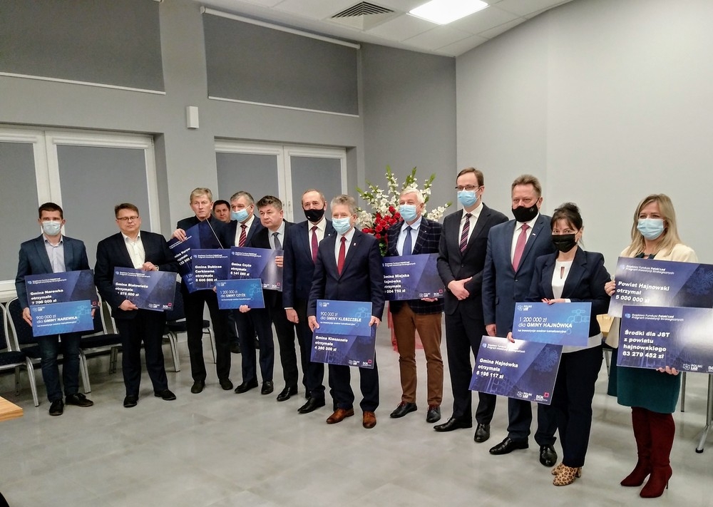 Zdjęcie pamiątkowe. Grupa osób trzyma symboliczne czeki.