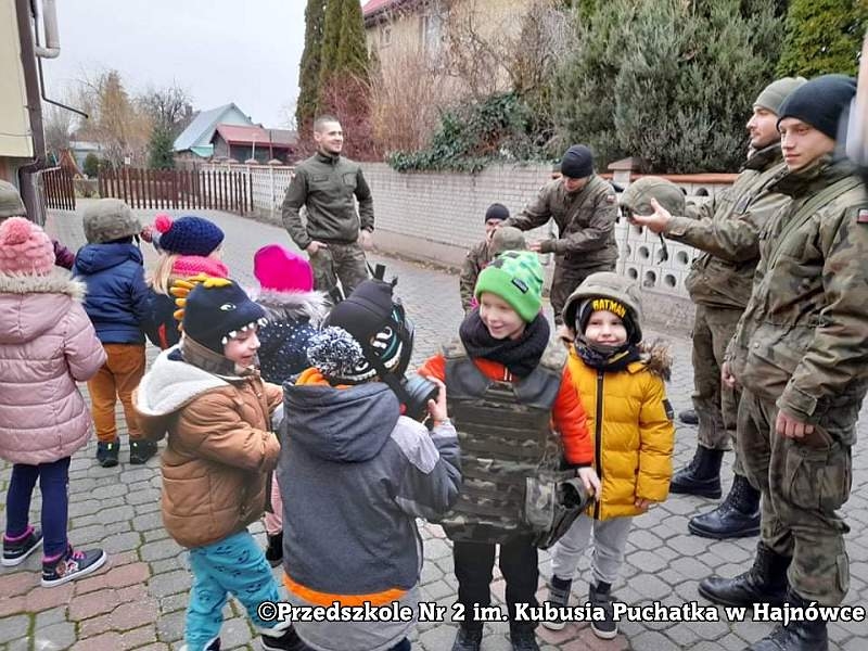 Zdjęcie dzieci i żołnieży, stoją na placu przed przedszkolem
