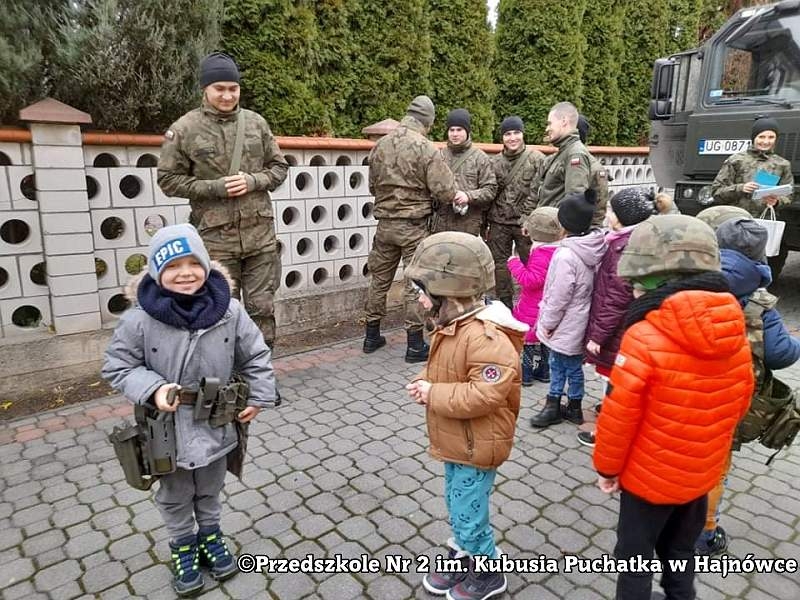 Zdjęcie dzieci i żołnieży, stoją na placu przed przedszkolem