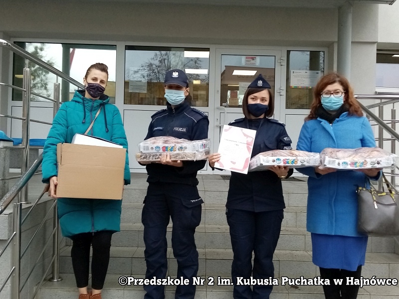 Zdjęcie pracowników przedszkola i policjantów stojących na schodach