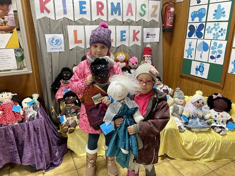 Dziecko,  którego rodzice zdecydowali się kupić lalki na kiermaszu.