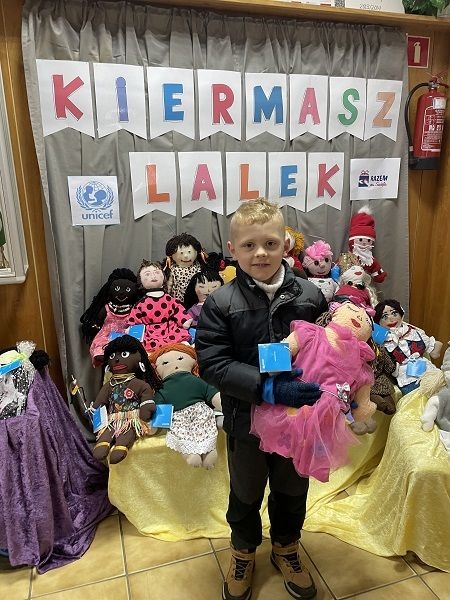 Dziecko,  którego rodzice zdecydowali się kupić lalki na kiermaszu.