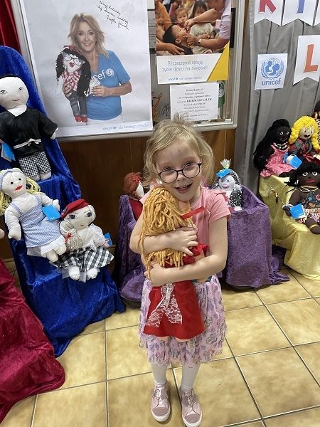 Dziecko,  którego rodzice zdecydowali się kupić lalki na kiermaszu.