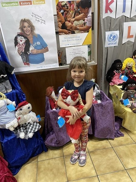 Dziecko,  którego rodzice zdecydowali się kupić lalki na kiermaszu.