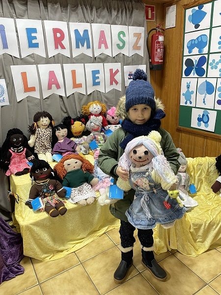 Dziecko,  którego rodzice zdecydowali się kupić lalki na kiermaszu.