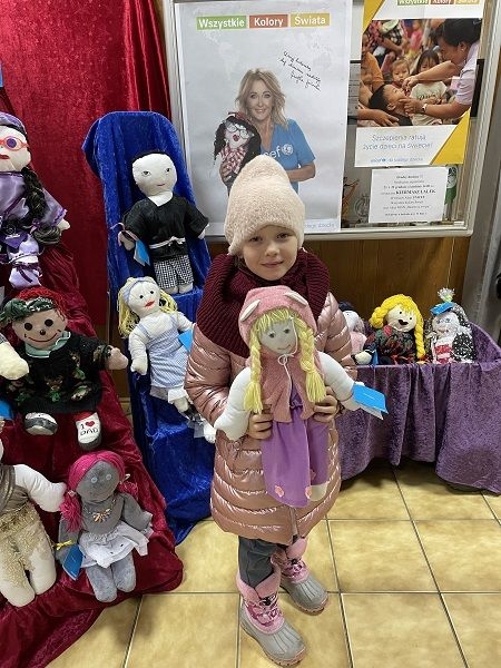 Dziecko,  którego rodzice zdecydowali się kupić lalki na kiermaszu.