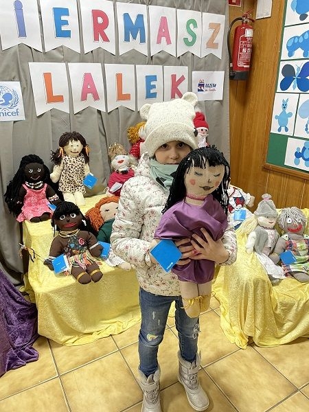 Dziecko,  którego rodzice zdecydowali się kupić lalki na kiermaszu.