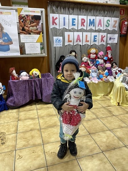 Dziecko,  którego rodzice zdecydowali się kupić lalki na kiermaszu.