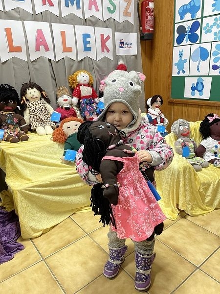 Dziecko,  którego rodzice zdecydowali się kupić lalki na kiermaszu.