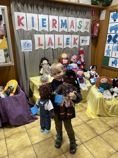 Dziecko,  którego rodzice zdecydowali się kupić lalki na kiermaszu.