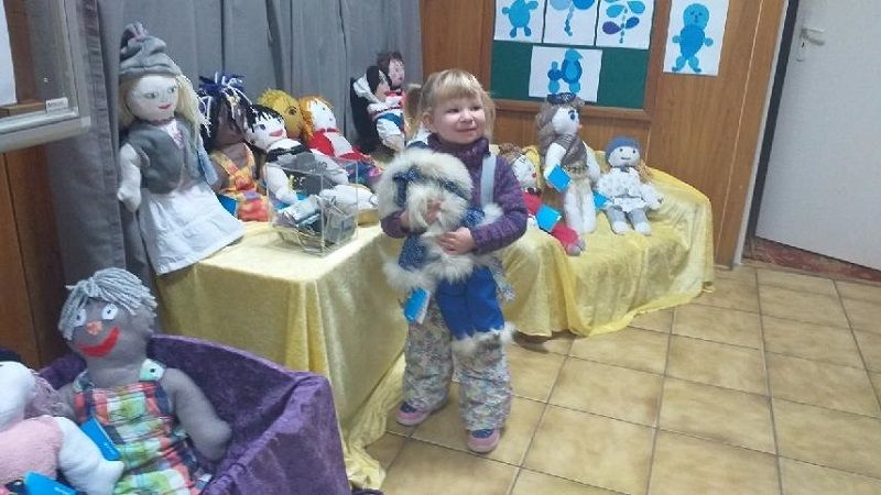 Dziecko,  którego rodzice zdecydowali się kupić lalki na kiermaszu.