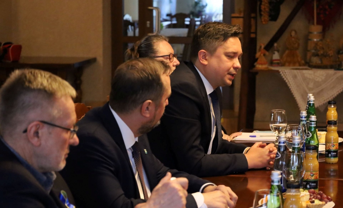 czterj mężczyźni siedzacy przy stole, jeden z nich udziela wypowiedzi