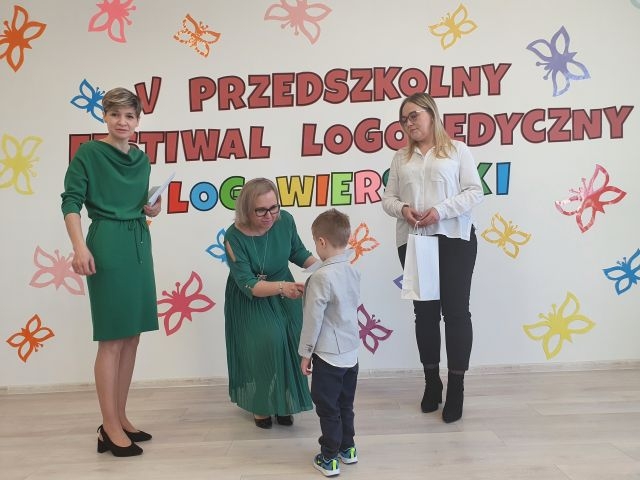 Pani Dyrektor wręcza nagrodę chłopcu ubranemu w błękitną koszulę.