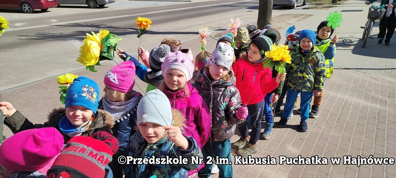 Dzieci podczas spaceru, trzymają żółte kwiaty.