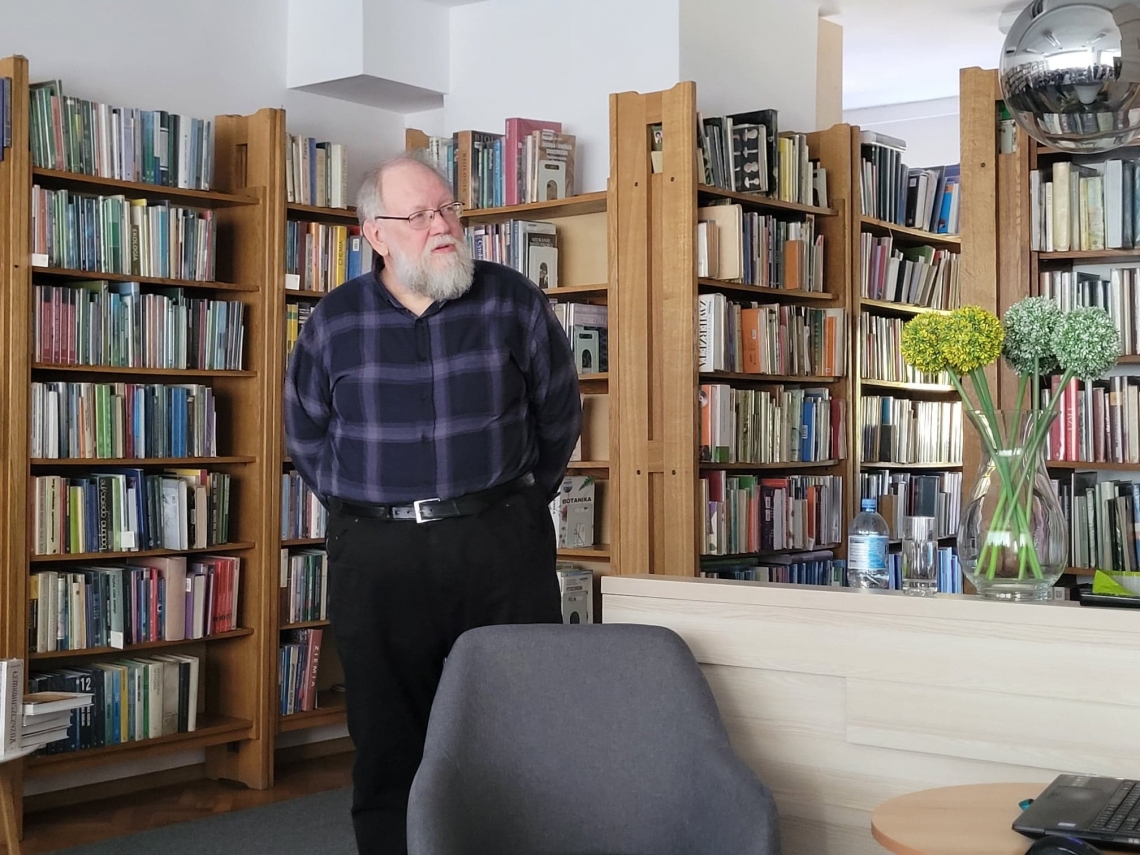 mężczyzna a za nim regały z książkami