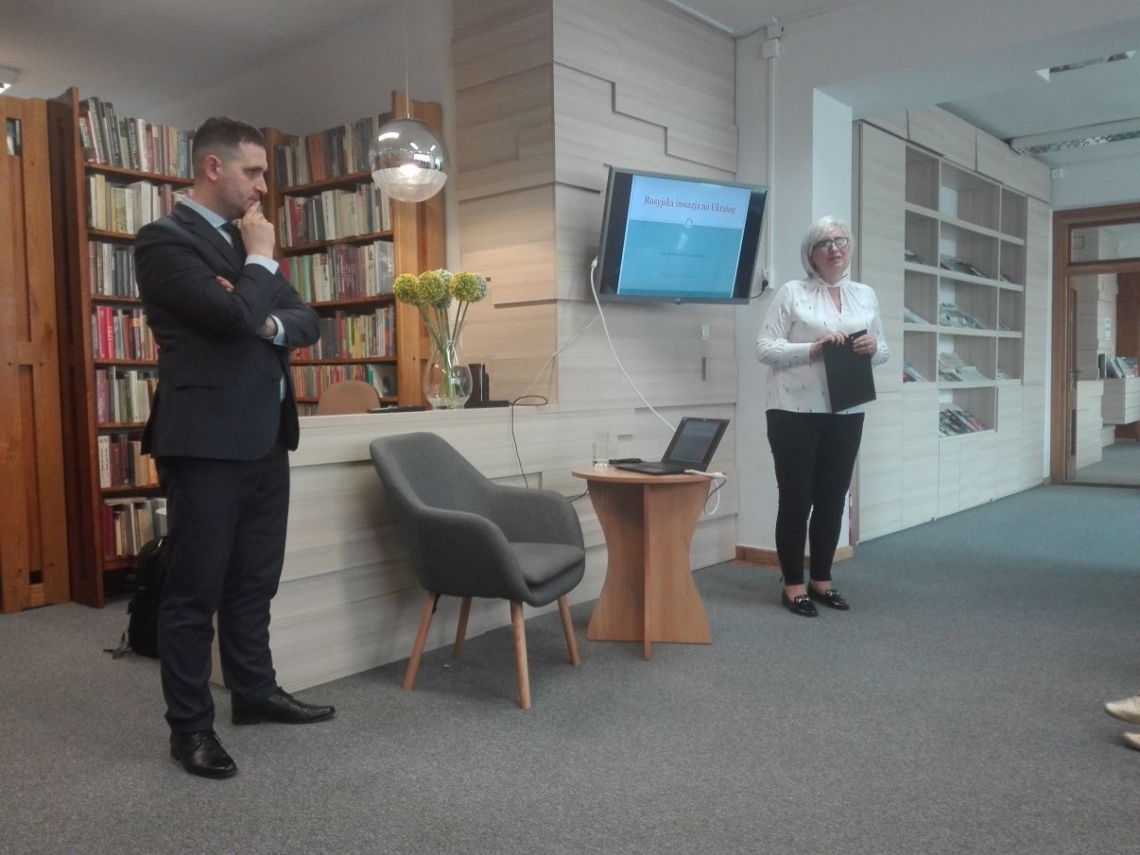 mężczyzna a za nim regały z książkami i kobieta przedstawiająca autora