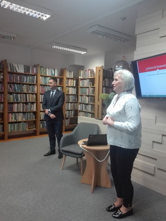 mężczyzna a za nim regały z książkami i kobieta przedstawiająca autora