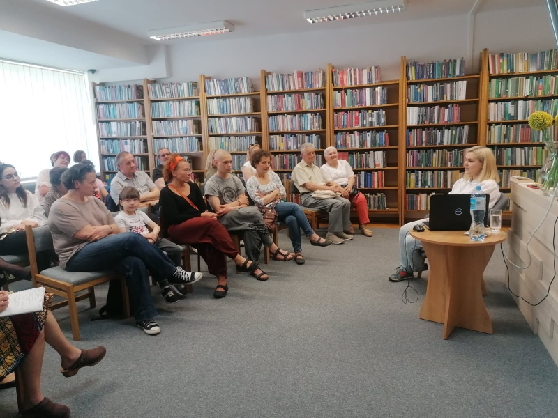 Autorka na spotkaniu z hajnowską publicznością, w tle regały z książkami