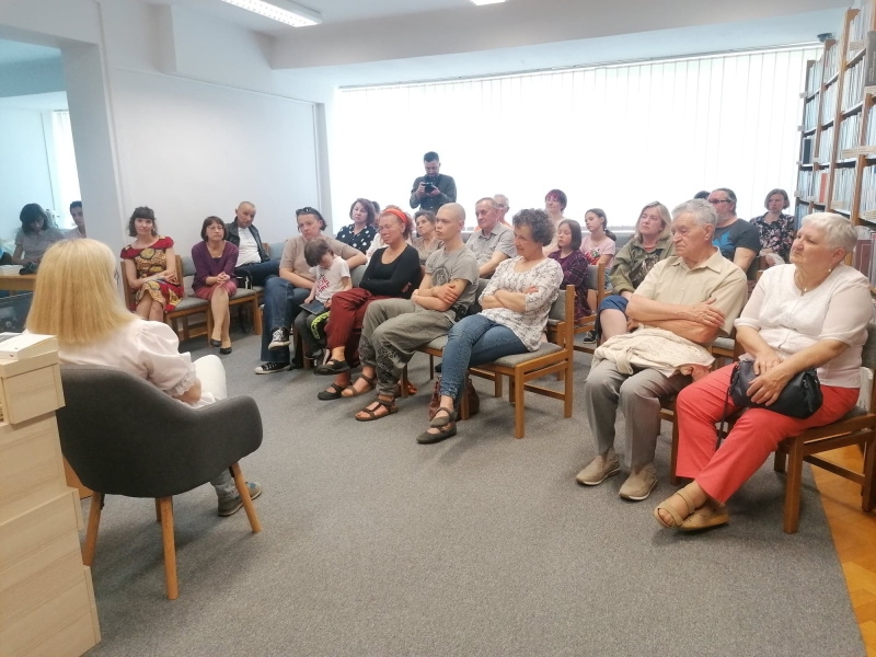 Autorka na spotkaniu z hajnowską publicznością, w tle regały z książkami