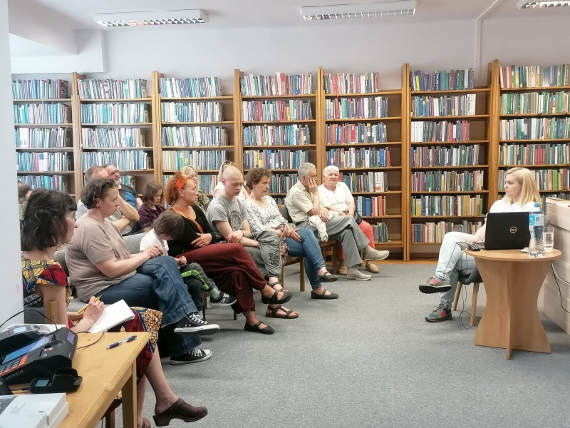 Autorka na spotkaniu z hajnowską publicznością, w tle regały z książkami