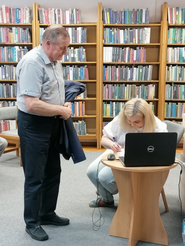 Autorka podpisuje książkę, obok stoi mężczyzna