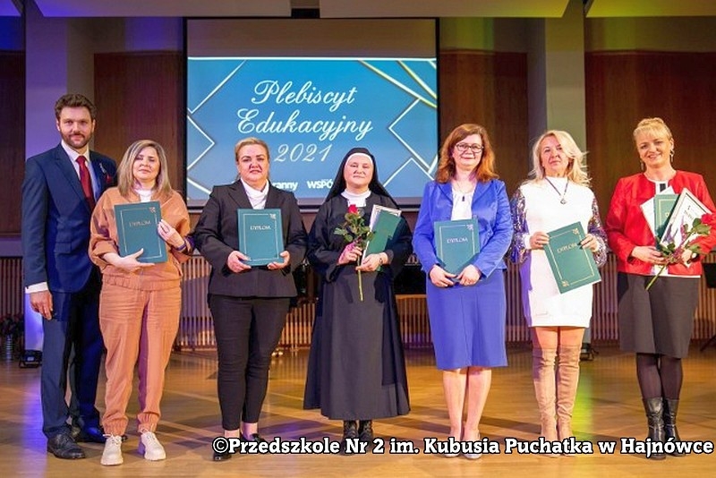 Na zdjęciu widać sześć stojącyk kobiet, po lewej stronie stoi mężczyzna w garniturze.