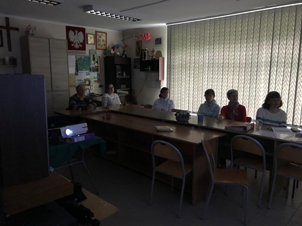 Kilka osób ogląda seans filmowy w przyciemnionej sali