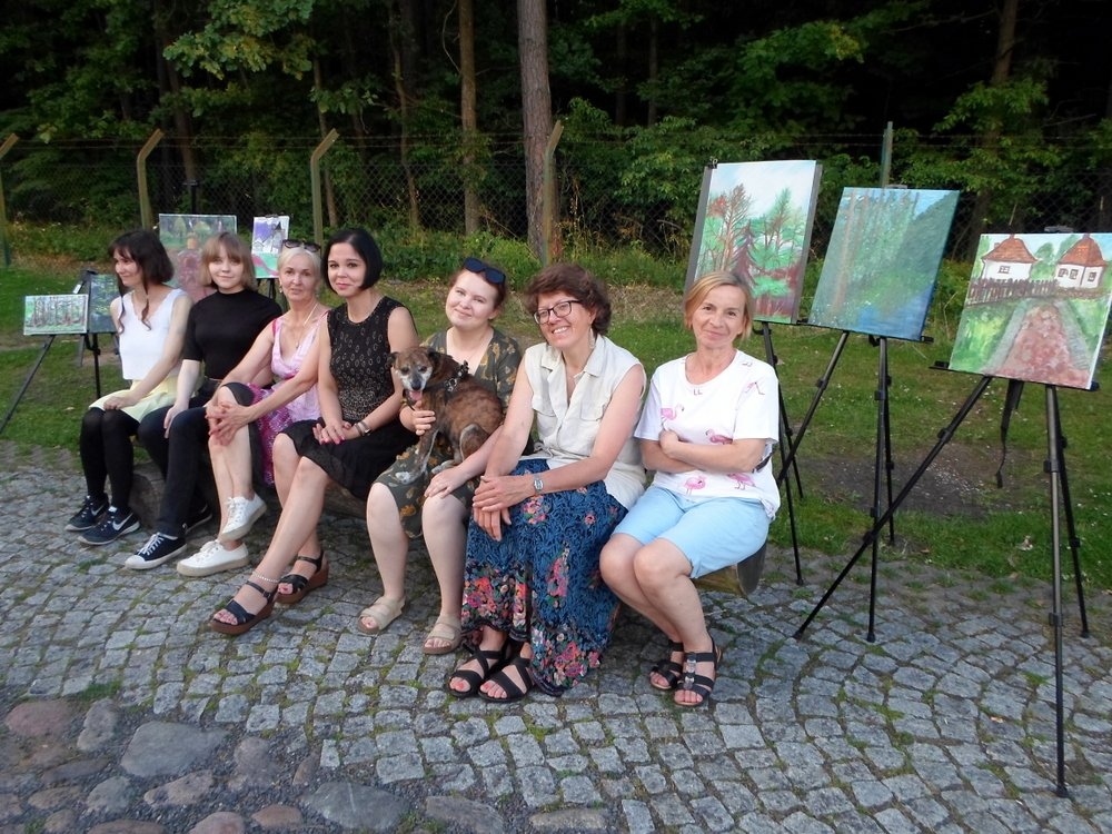 Kobiety siedzą na ławce na tle lasu.