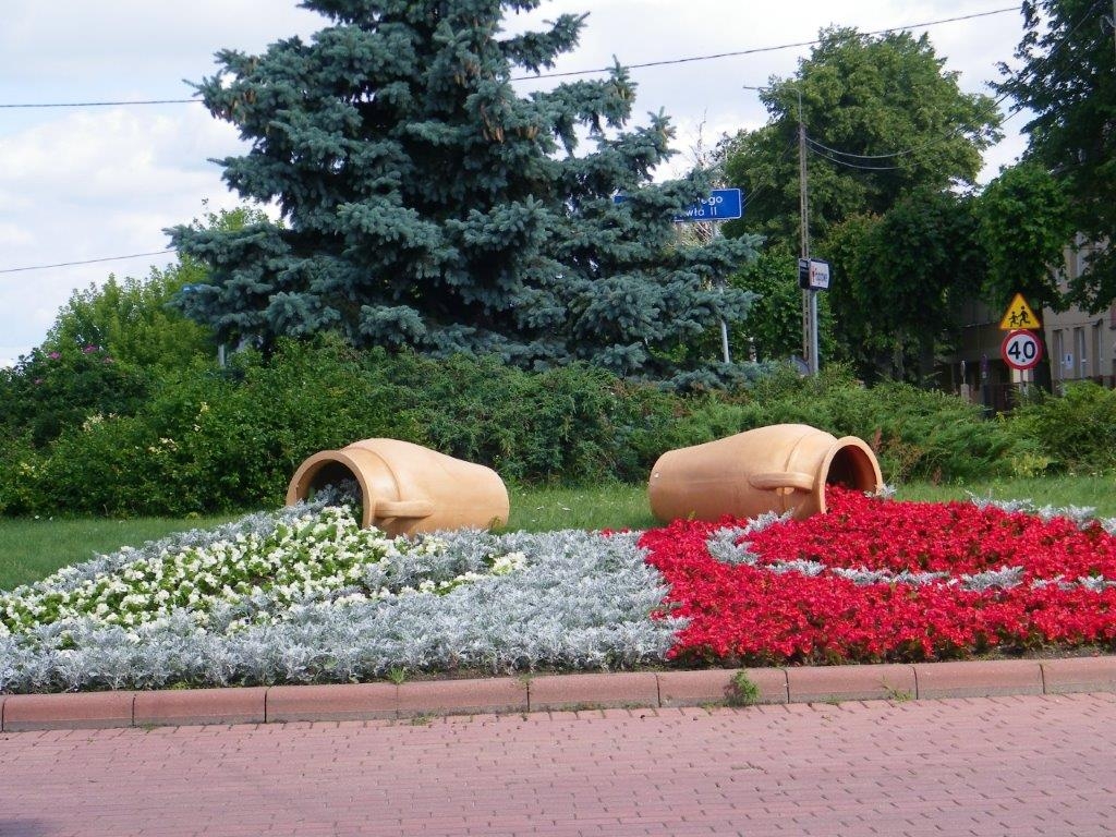 Dwa dzbany, z których "wylewają się kwiaty w czerwonymi białym kolorze.