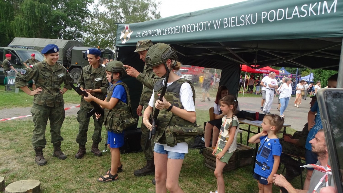 Mieszkańcy przymierzają umundurowanie wojskowe.
