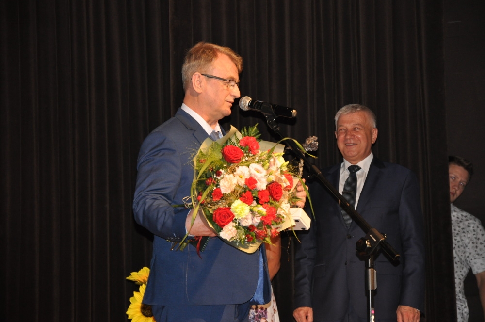 Jerzy Pawluk trzyma bukiet kwiatów i statuetkę.