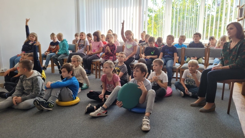 Zdjęcie grupowe, na którym siedzą na podłodze i na krzesłach uczniowe hajnowskich szkół.